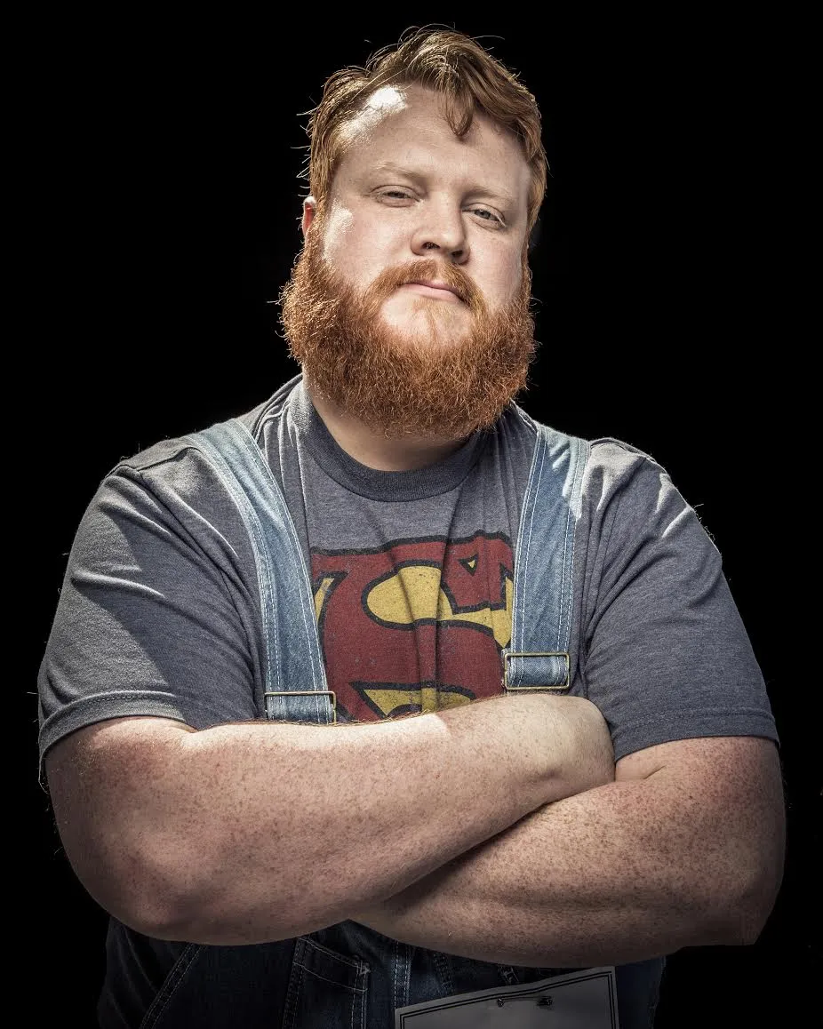 Lee Quessenberry studio portrait in overalls and a Superman t-shirt