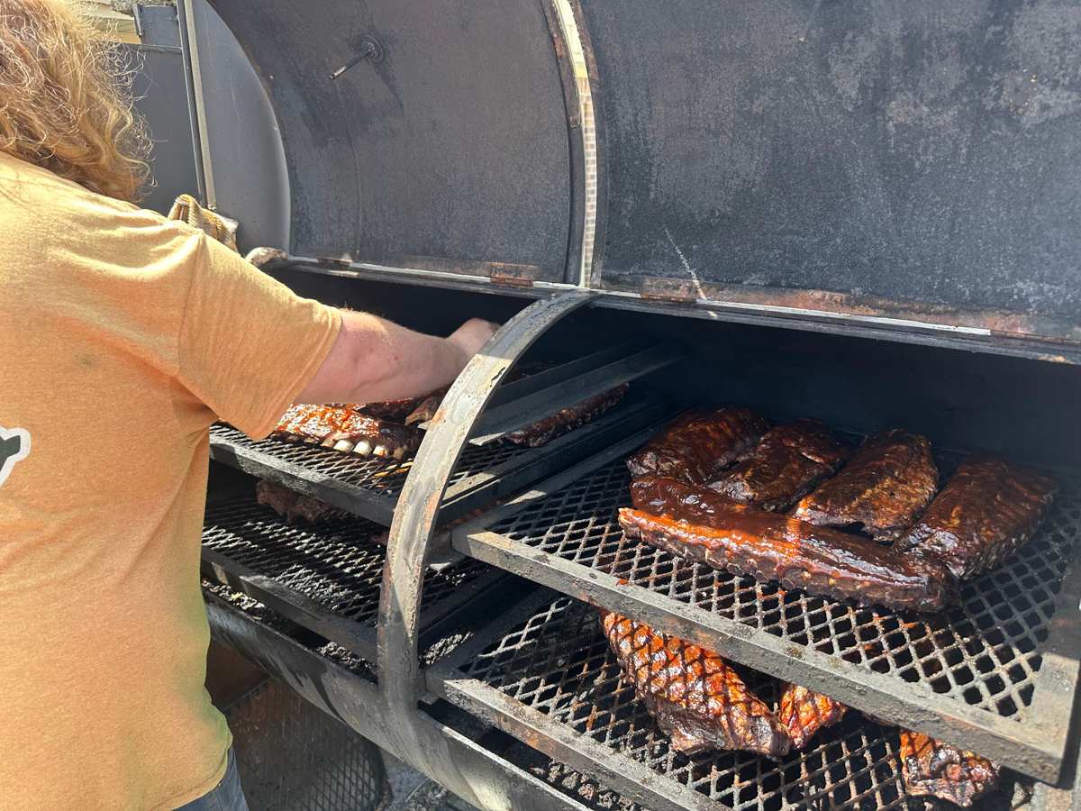 Sauced racks of ribs on the shelves of an offset smoker